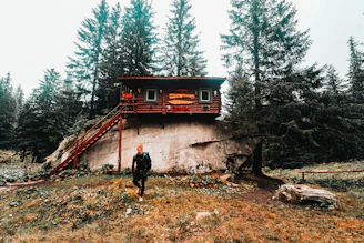 Camp co-host sharing tips with runners beside a rustic wooden cabin.