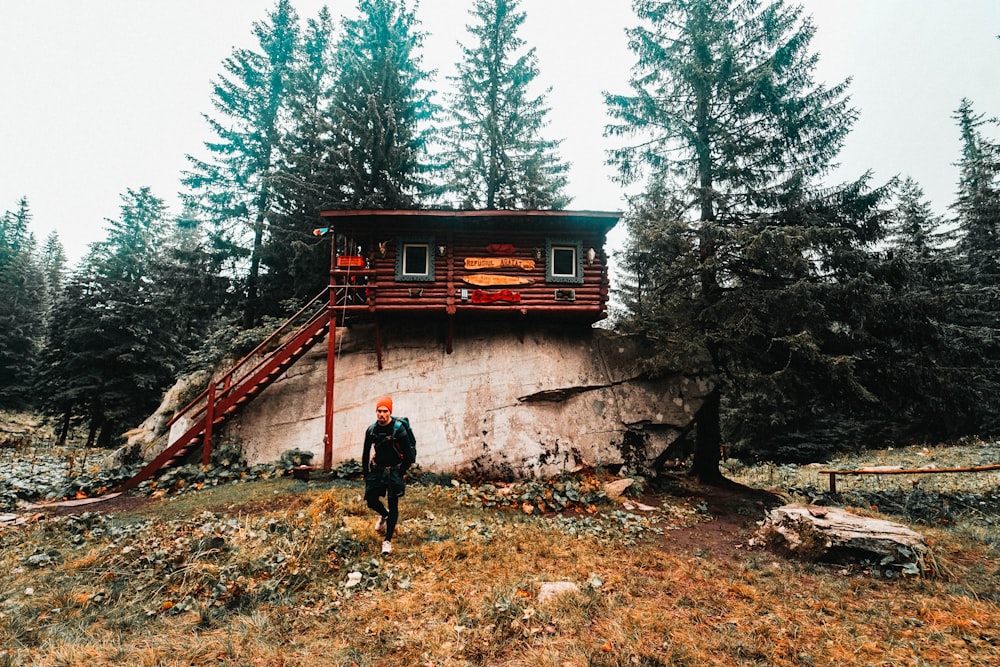 man standing in front of house on rock formation