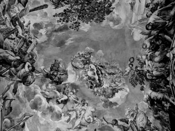 A detailed fresco painting depicts a celestial scene filled with mythological figures, including cherubic children and deities, surrounded by clouds and a lush tree. Intricate architectural elements and classical motifs frame the artwork, while various figures engage in dynamic poses.