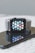 A smartwatch with a gray woven band is positioned on top of a smartphone with a black screen, which reflects the watch's face displaying multiple colorful app icons.