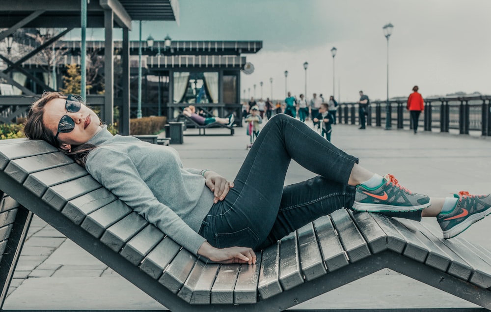 woman laying on bench during daytime