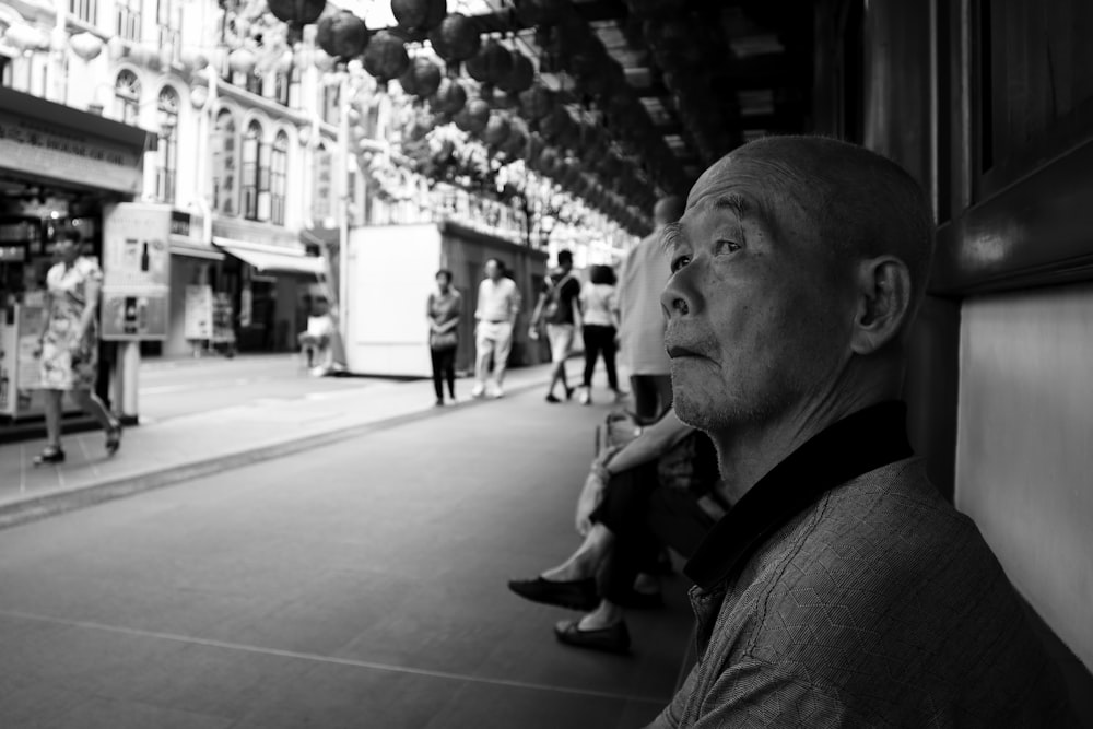 grayscale photo of man sitting on bench