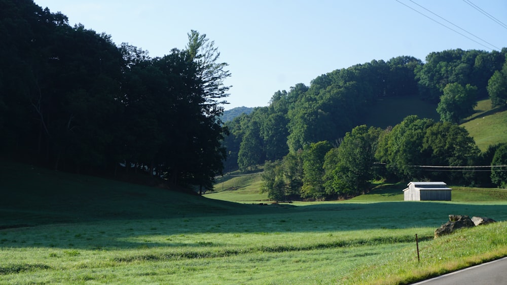 a grassy field with a barn in the distance