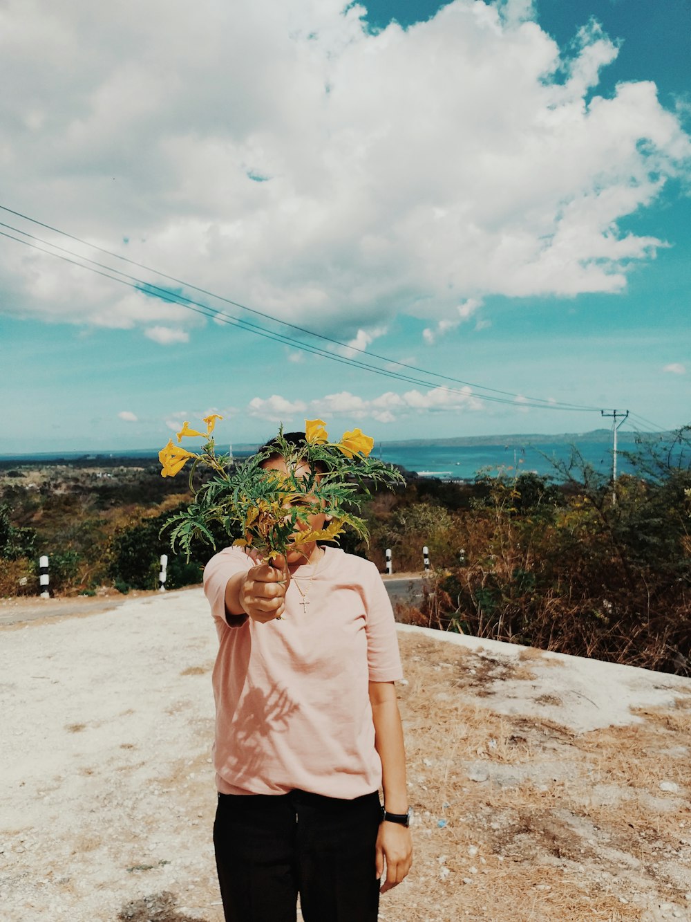 Donna in piedi che tiene i fiori gialli durante il giorno