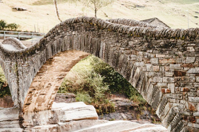 Historic stone bridge crossing a gentle stream along the path in Savoie.