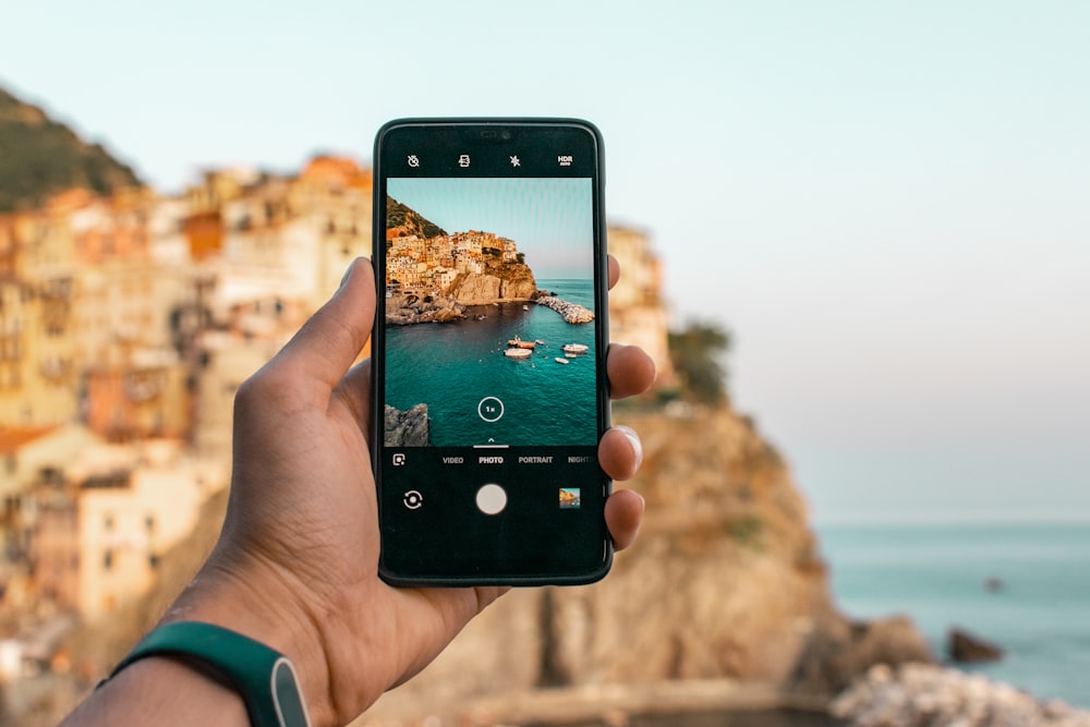 person holding a phone near cliff during daytime