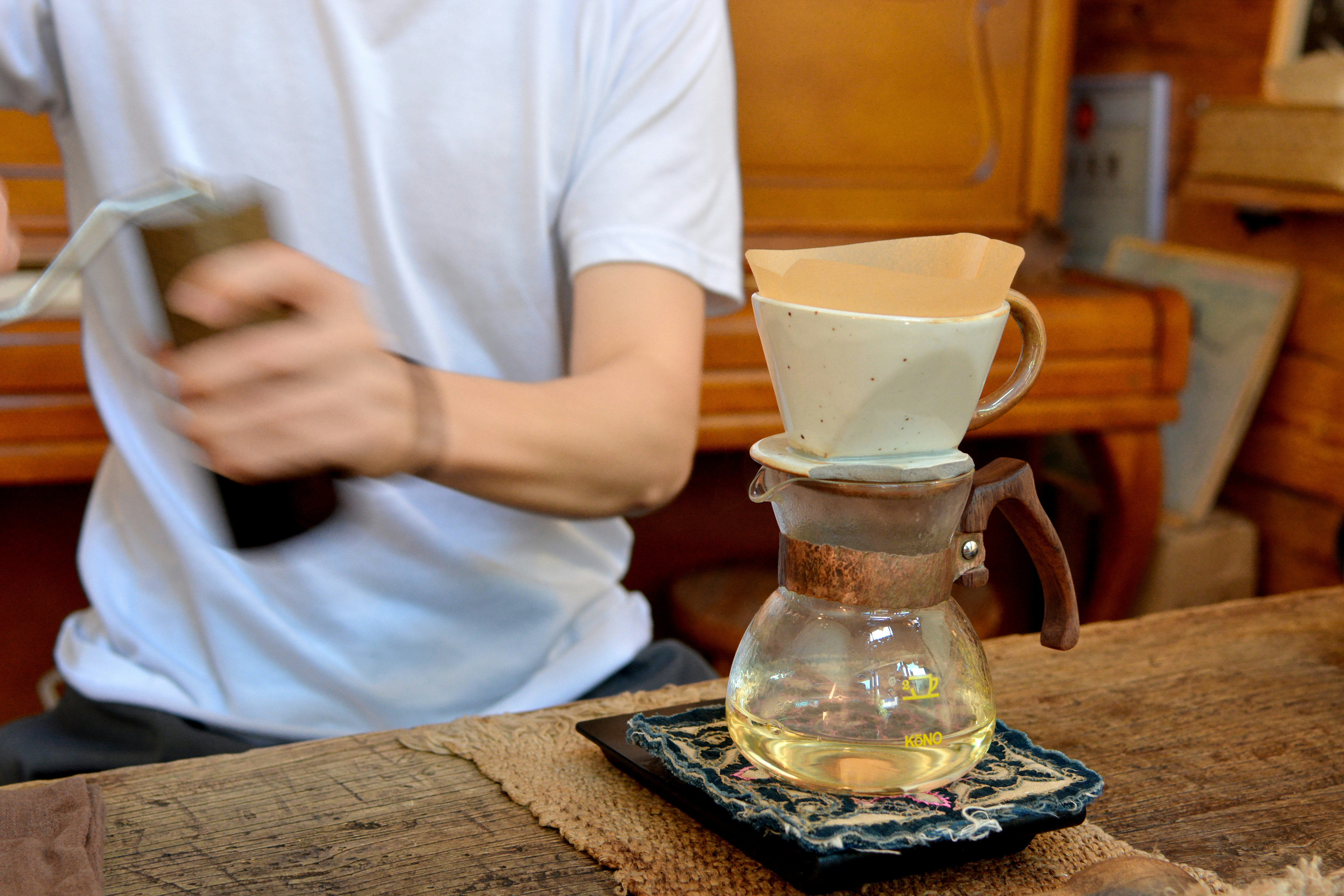 Man brewing pour-over coffee into a glass server
