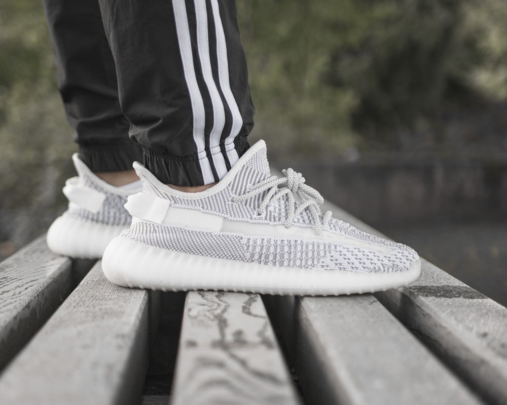 person wearing grey sneaker standing on wooden surface