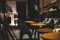 A cozy indoor event space with vintage-style chairs and wooden tables decorated with candles.