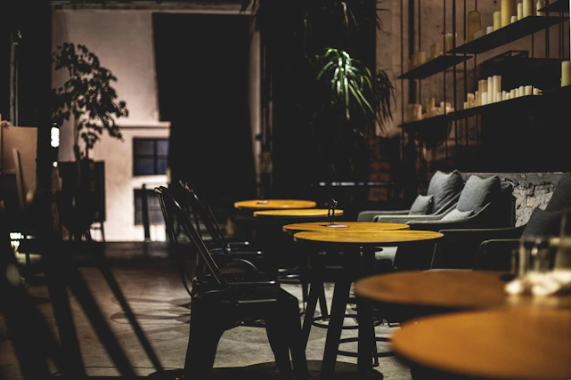 Cozy interior of igualainn with dark green accents and softly lit tables ready for guests.