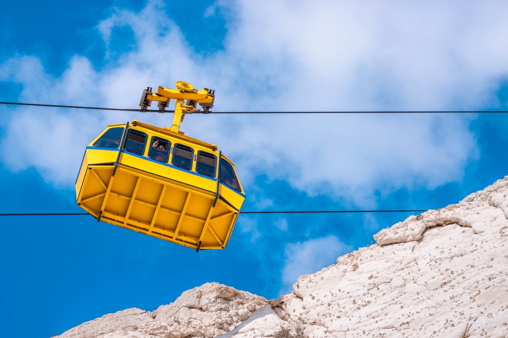 low-angle photography of yellow cable car under cloudy sky
