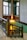 A beautifully designed staircase with ornate wooden railing and intricate stained glass windows. The wooden craftsmanship is detailed and complements the warm lighting fixtures on the walls, creating a vintage or historical atmosphere.