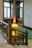 A beautifully designed staircase with ornate wooden railing and intricate stained glass windows. The wooden craftsmanship is detailed and complements the warm lighting fixtures on the walls, creating a vintage or historical atmosphere.