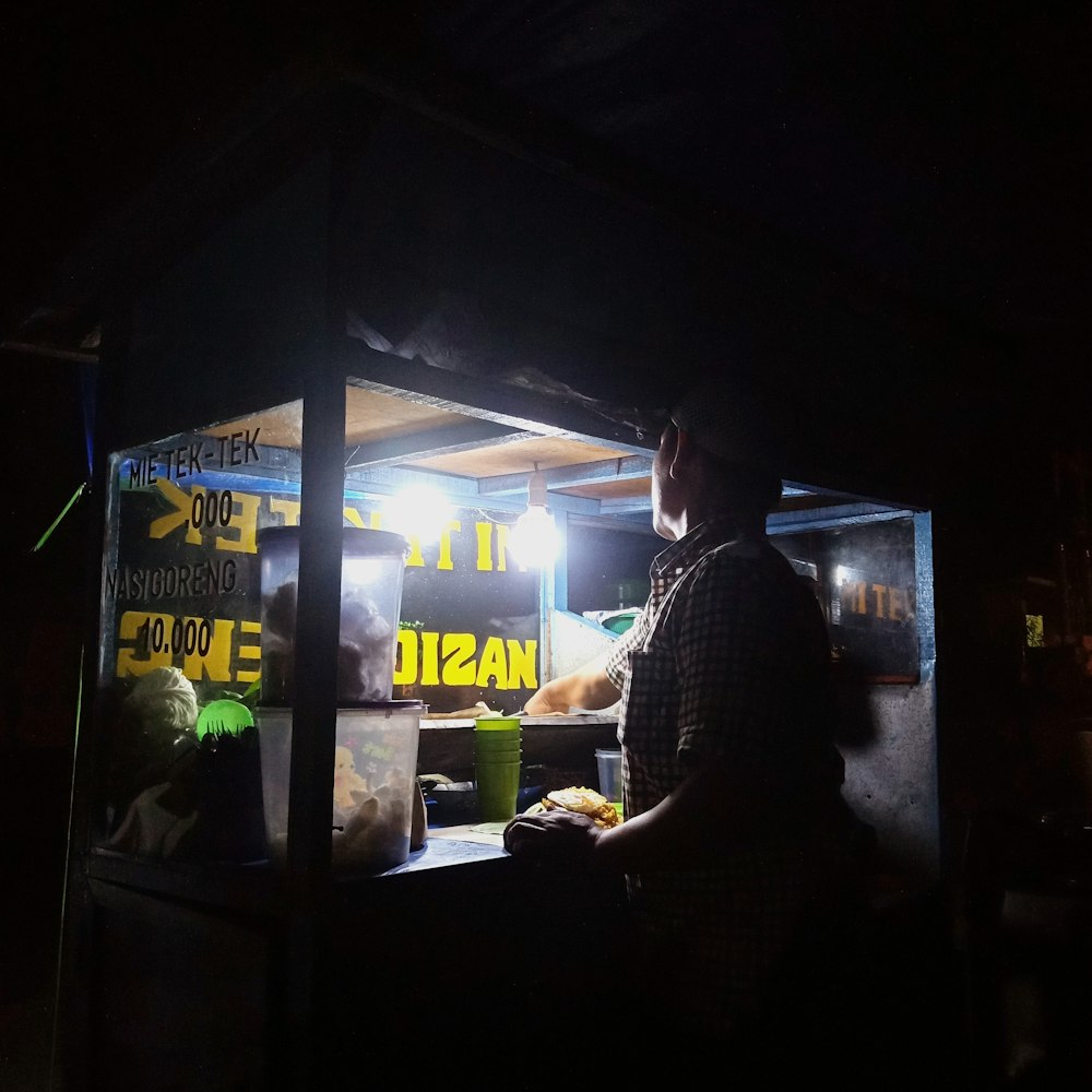 man standing in front of food cart during night time