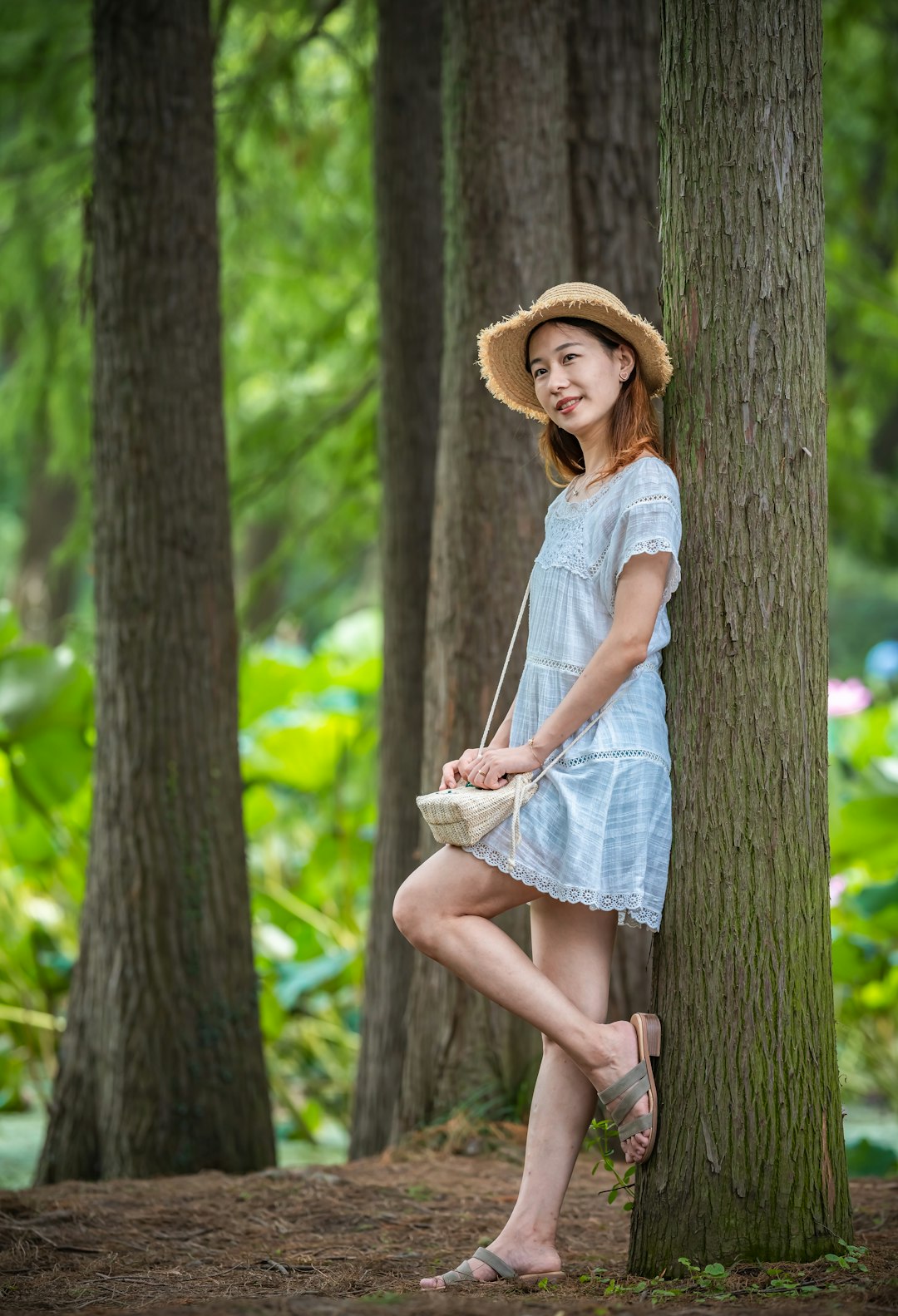 woman wearing blue dress leaning on tree