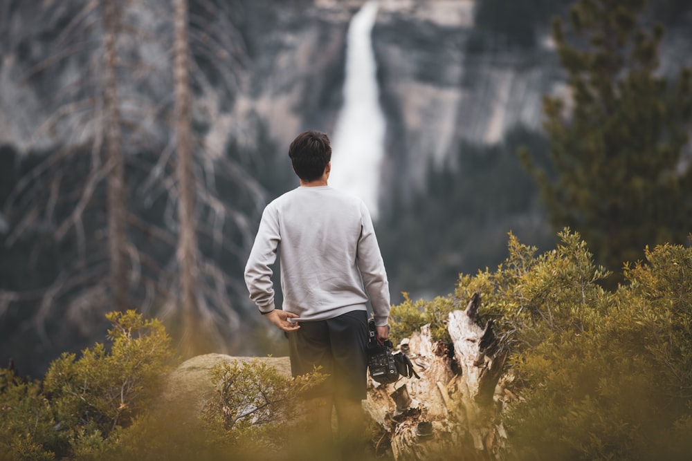 selective focus photography of standing man in gray shirt overlooking waterfalls
