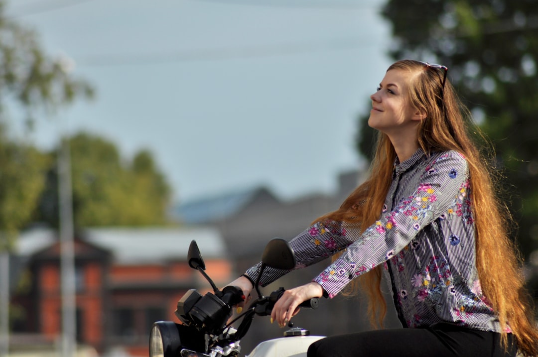 woman wearing purple floral long-sleeved top riding motorcycle