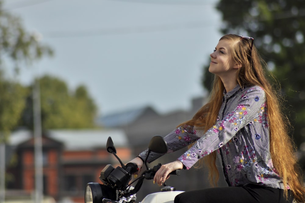 woman wearing purple floral long-sleeved top riding motorcycle