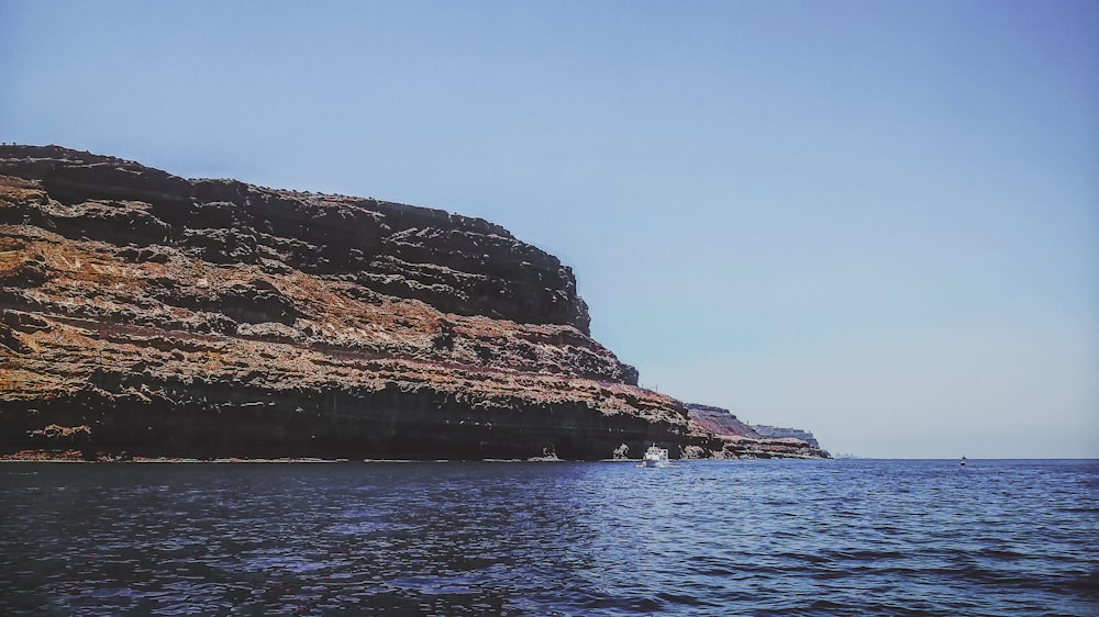 body of water across brown cliff during daytime