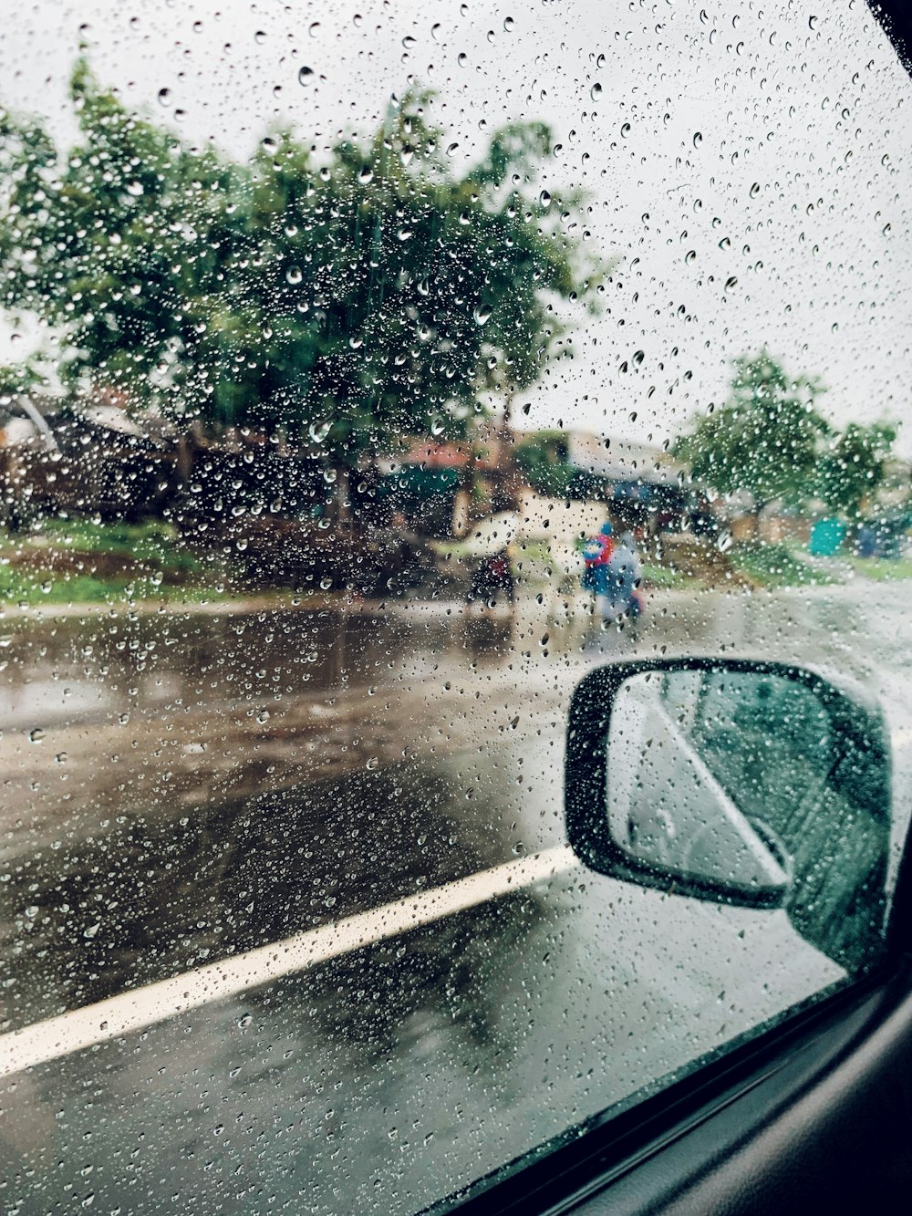 Una vista de una calle empapada de lluvia desde la ventana de un automóvil