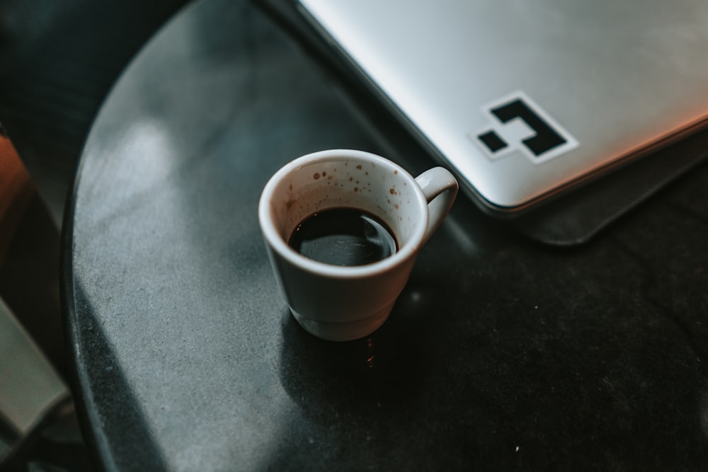 half empty coffee filled mug on black surface