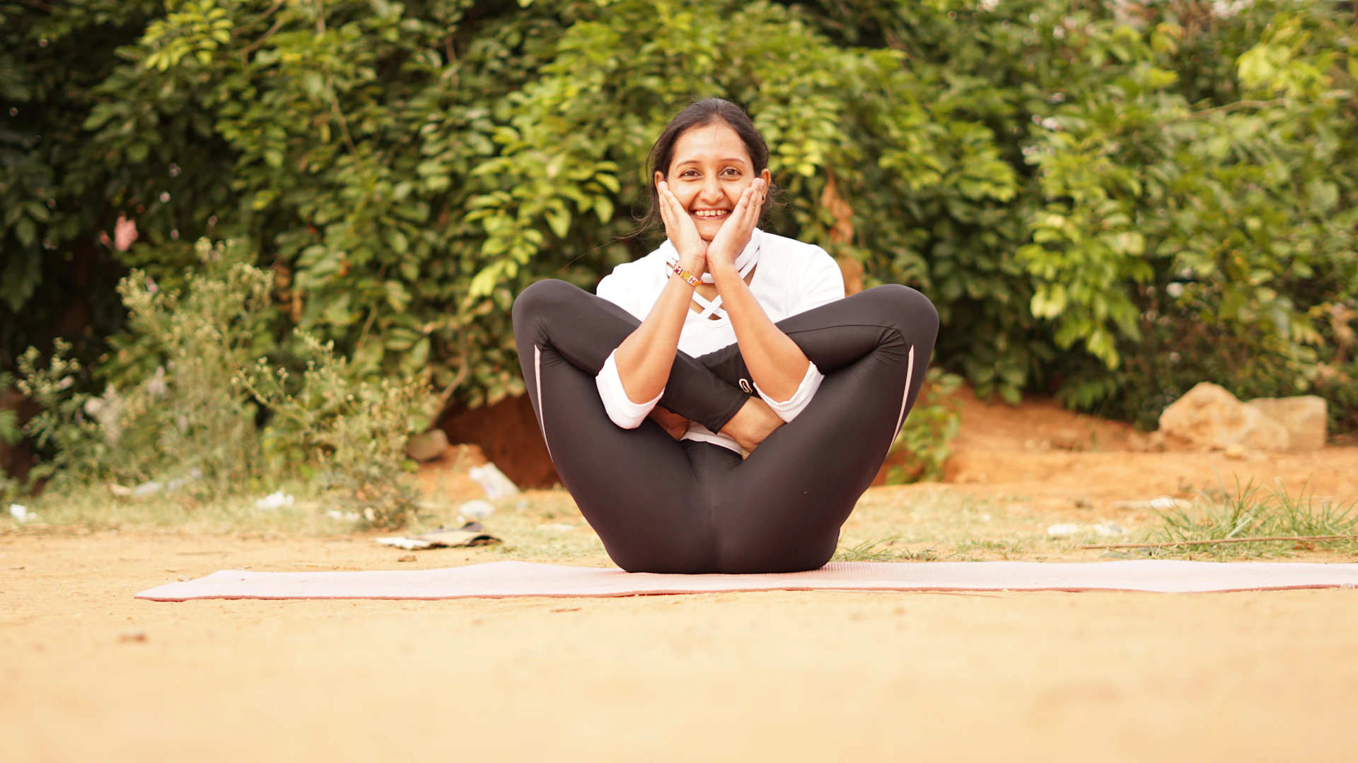 A serene yoga practitioner meditating outdoors at sunrise with soft green foliage in the background.