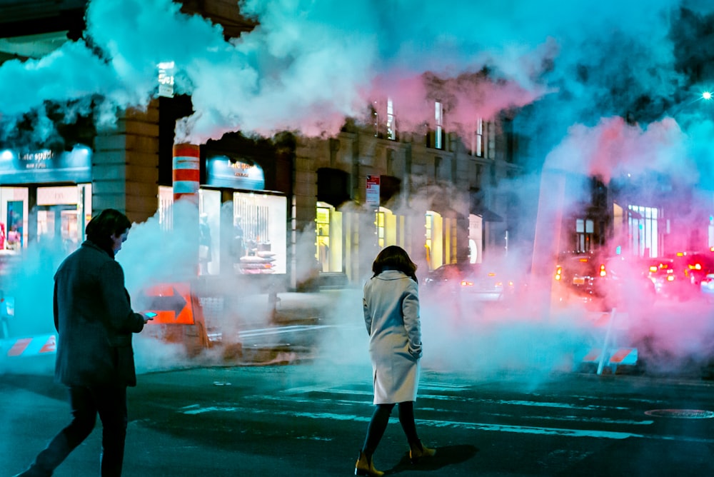 two persons walking across the street near smoke