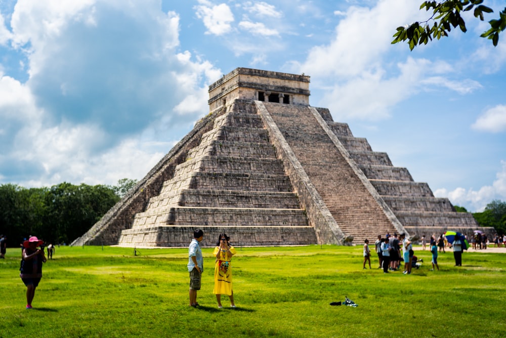 people standing on grass near pyramid during day