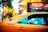 A yellow taxi with a roof-top advertisement for a 'Biggest Sale of the Year' at a retailer is visible. The advertisement highlights a sale on all beds, providing a specific address in the Flatiron District. The taxi's side is marked with a number, and the window reflects some trees and sky. In the background, blurred greenery and city elements create a vibrant urban setting.
