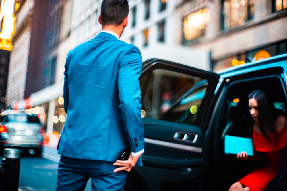 man wearing blue suit standing beside vehicle