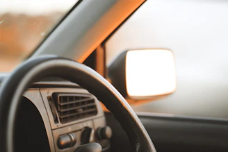 A friendly instructor helping a young learner driver adjust the mirrors inside a car.