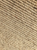 A close-up view of tightly wound beige rope coils, displaying a rough texture with visible fibers and strands.