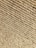 A close-up view of tightly wound beige rope coils, displaying a rough texture with visible fibers and strands.