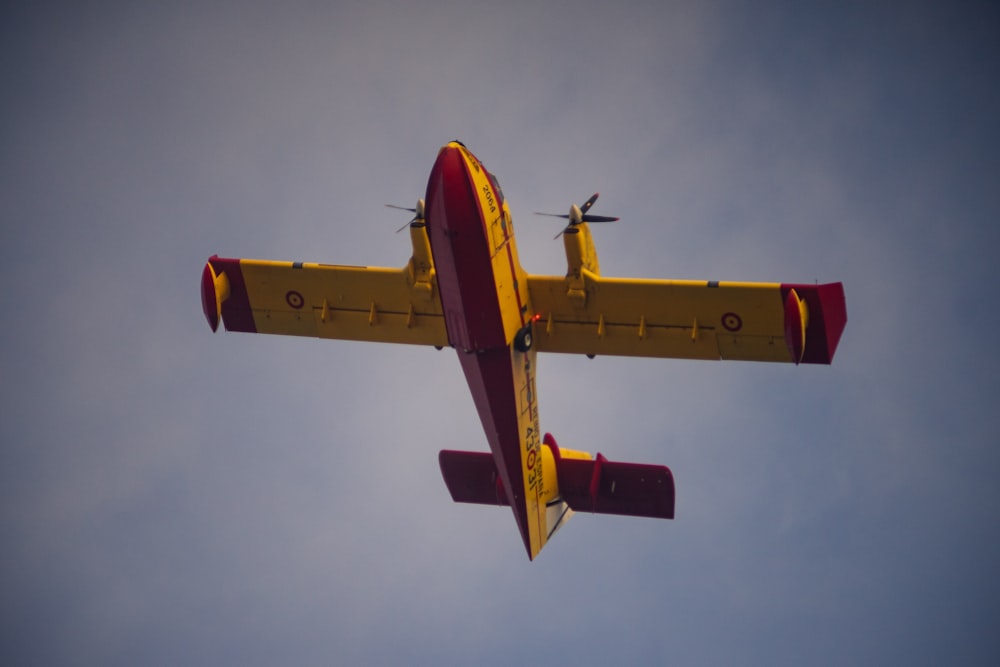 red and yellow propeller plane in flight
