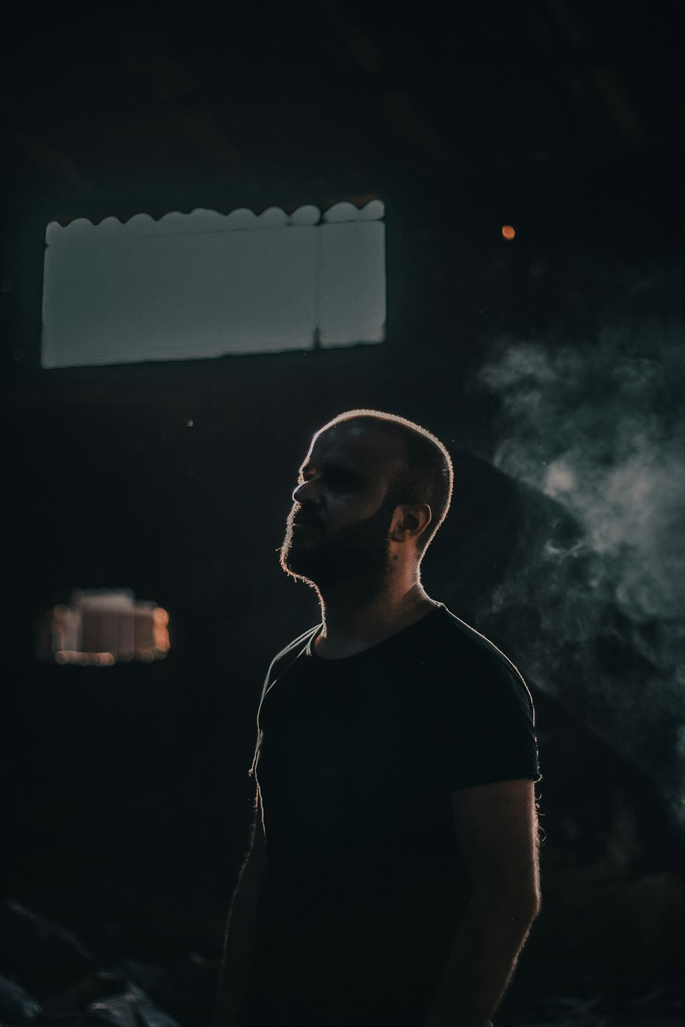 a man standing in the dark with smoke coming out of his mouth