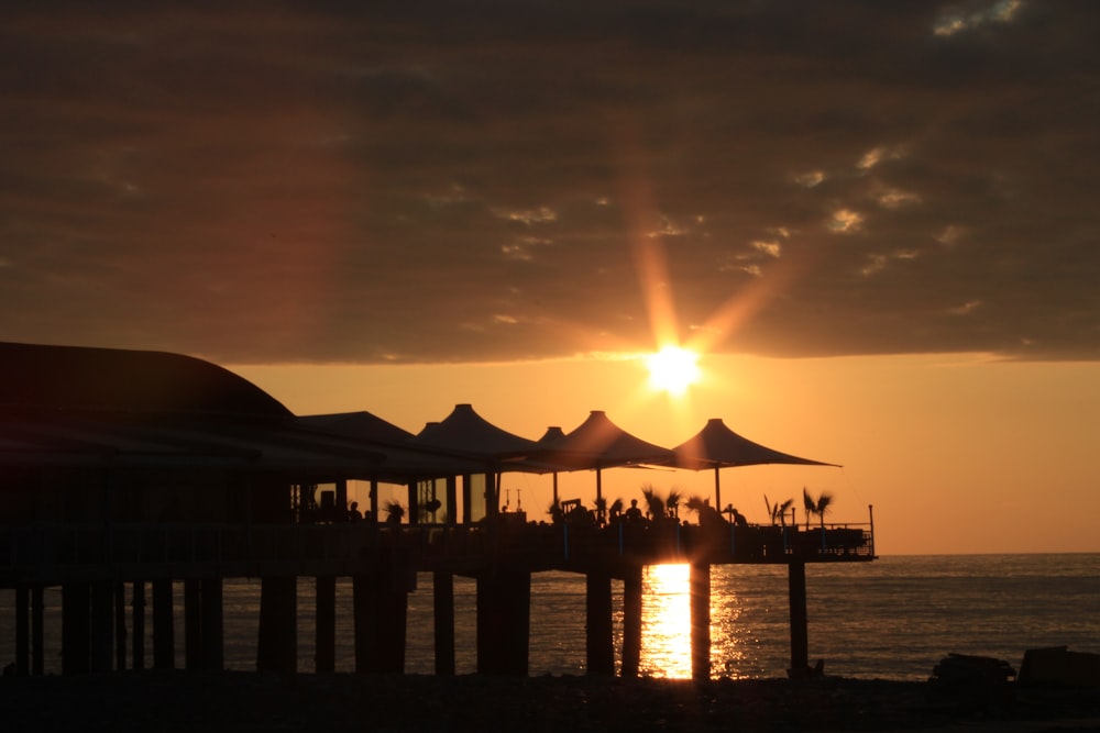 silhouette of beach house under orange skies