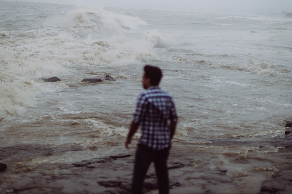 man standing beside seashore during daytime