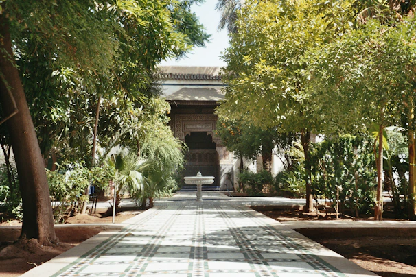 A serene garden path leading to the temple entrance, lined with blooming jasmine and marigold garlands.
