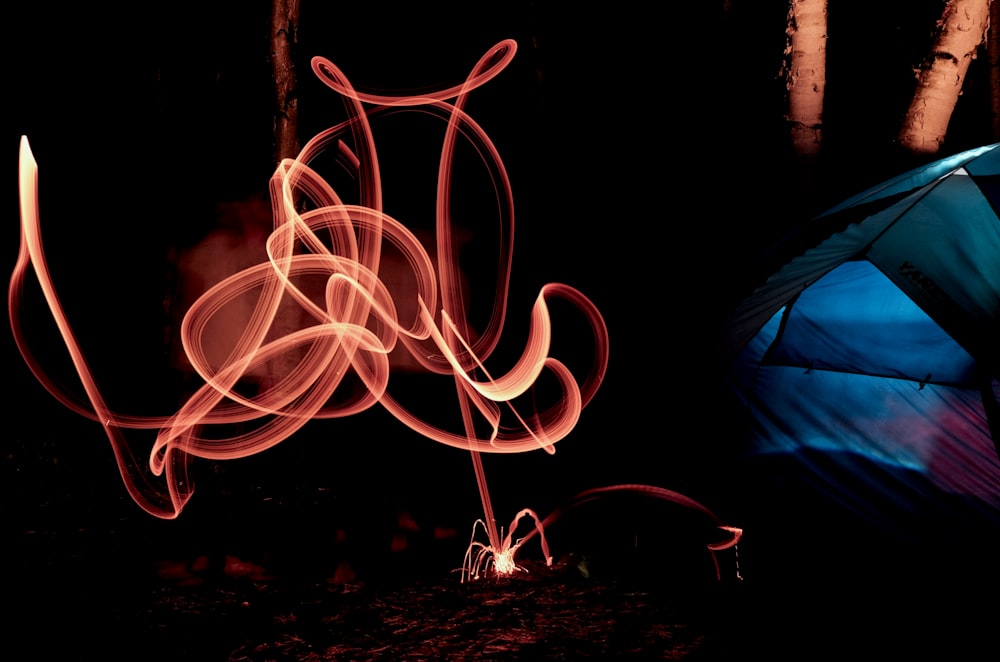 a blue tent and a red fire in the dark