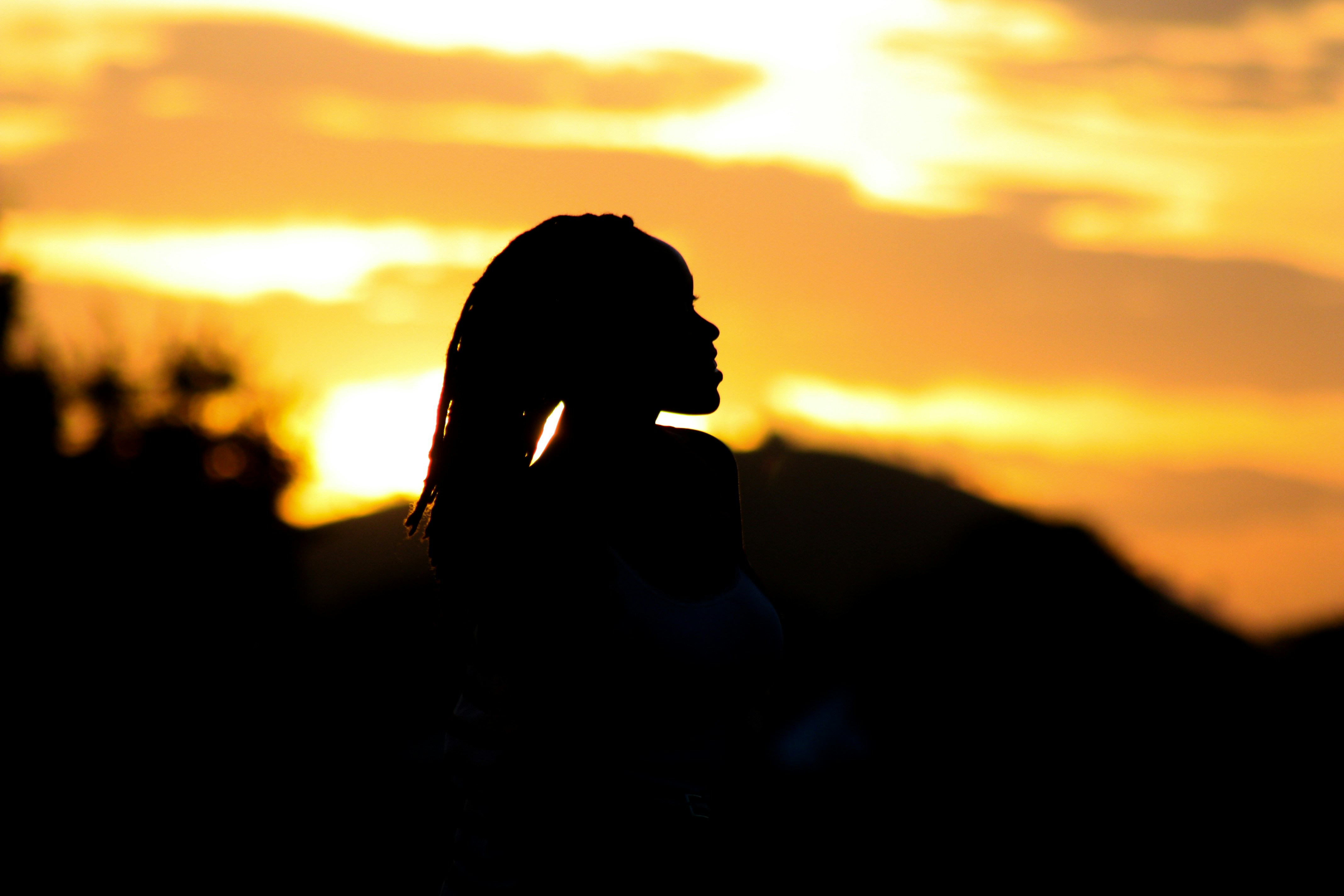 A silhouette of a young woman looking at a sunset, with an inspirational quote overlay