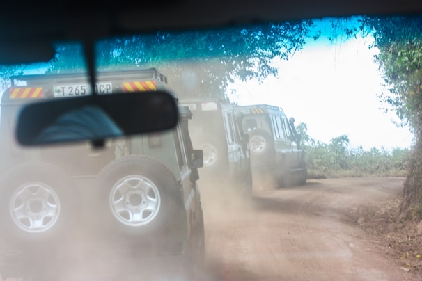 Group of off-road vehicles kicking up dust on a rugged Texas trail at sunset.