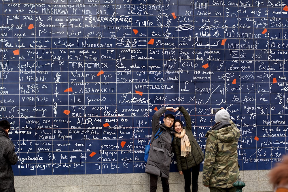 a group of people standing in front of a wall covered in writing