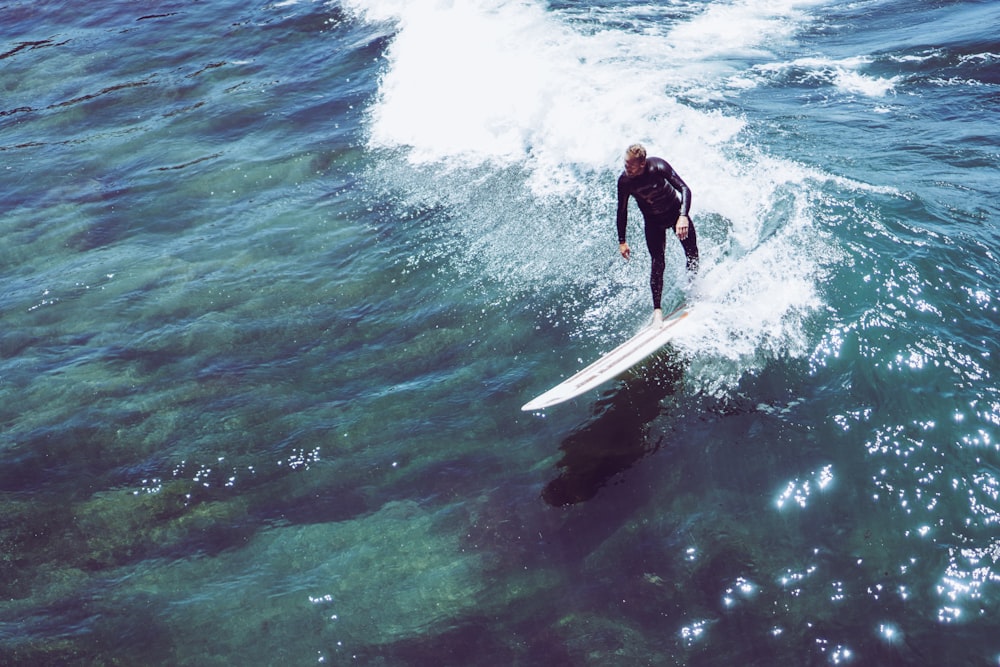 Mann reitet auf weißem Surfbrett kurz davor, auf Meereswellen zu surfen