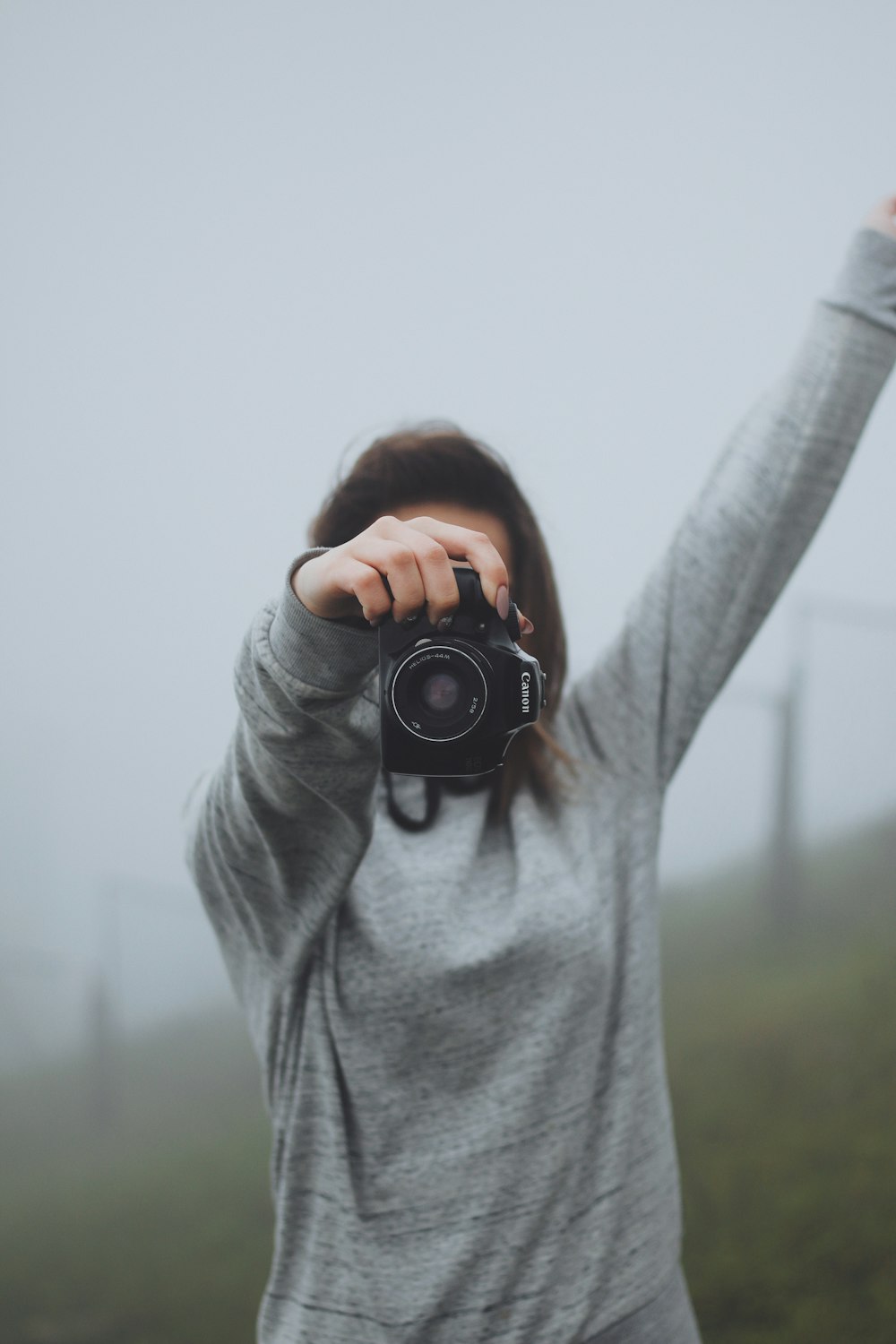 photographie sélective de mise au point d’une femme tenant un appareil photo reflex numérique