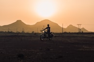 Sunset silhouette of a motorbike against a backdrop of Bali’s rolling hills and temple rooftops.