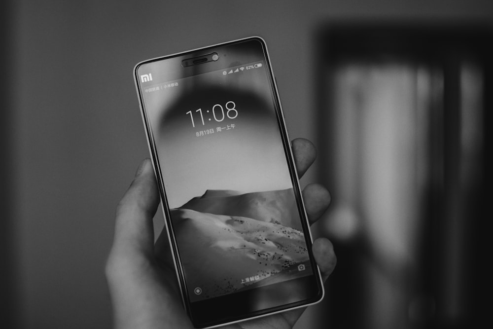 grayscale photography of person holds smartphone