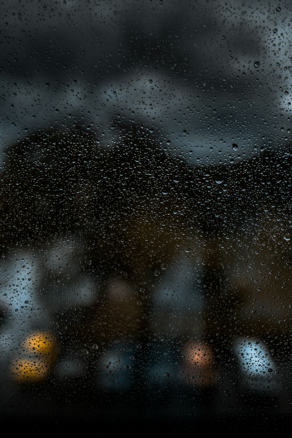 La pioggia cade su una finestra con uno sfondo sfocato