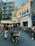 A bustling urban street featuring a variety of parked motorbikes and scooters on the side. In the foreground, a man rides a bicycle taxi, or pedicab, with a basket in front. The buildings are multi-story with a slightly worn appearance, displaying a blend of modern and older architectural styles. Signs in Chinese characters adorn the shops, adding to the vibrant street scene. People are walking by, contributing to the lively atmosphere.
