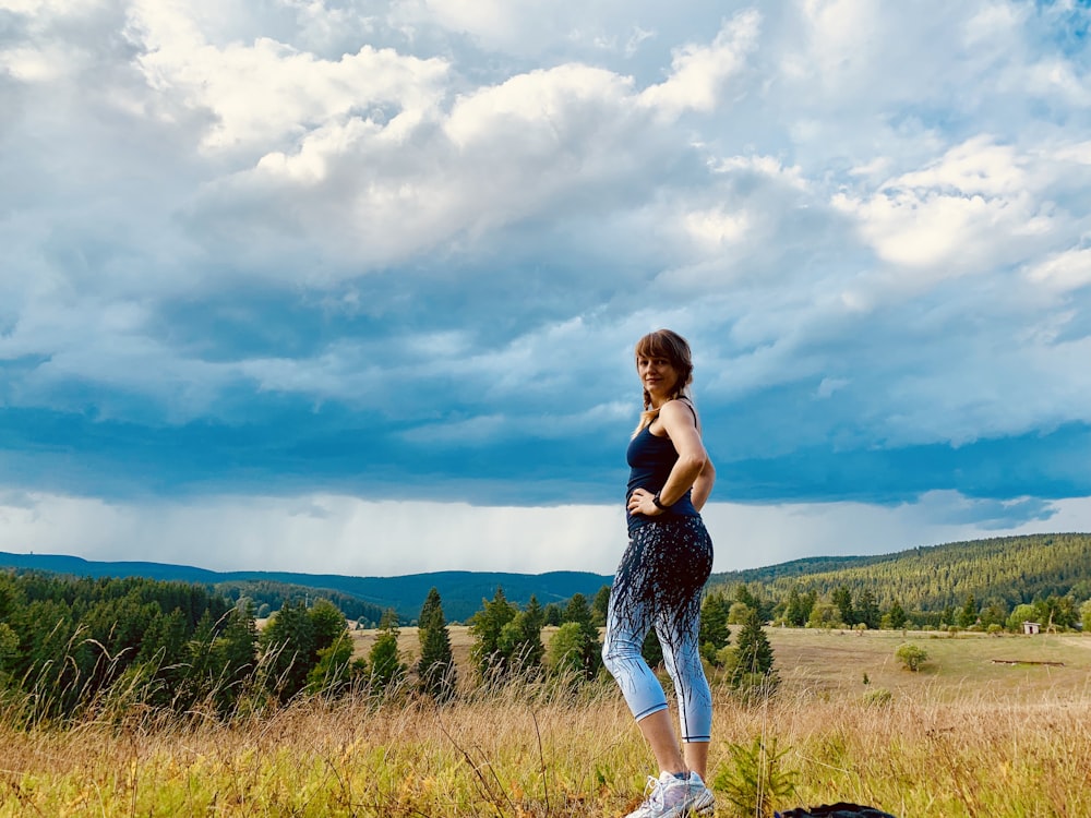 woman wearing black and teal ju7mp suit walking on grass field