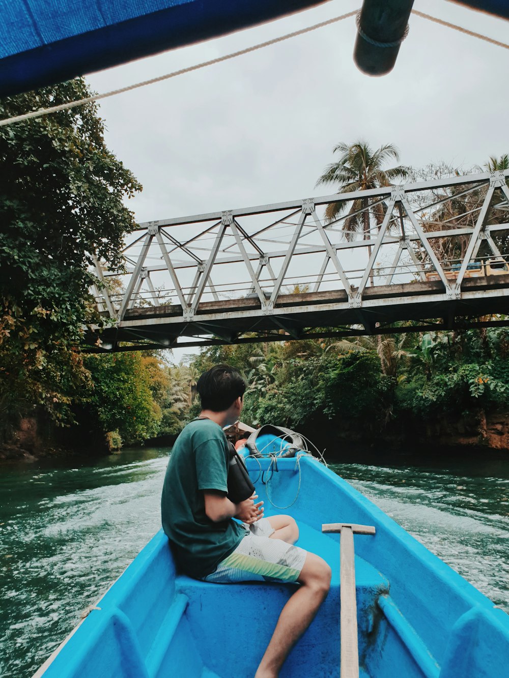 boy sitting on boat near bridge